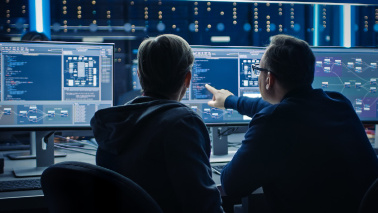 Zwei Entwickler sitzen am Computer und besprechen die Entwicklung einer KI für die Ursachenanalyse in der Produktion